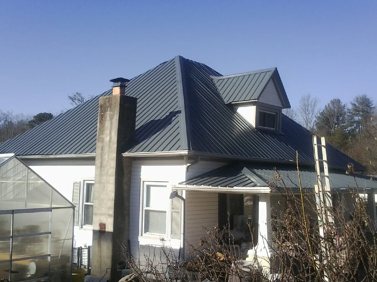 Dark blue standing seam metal roof on a white farmhouse with dormer — Slate & Tile Roof Repair by Roofing Brothers in Delco