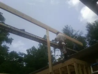 Carpenter setting a ridge beam over a new addition frame — Ice Dam Removal by Roofing Brothers in Delco