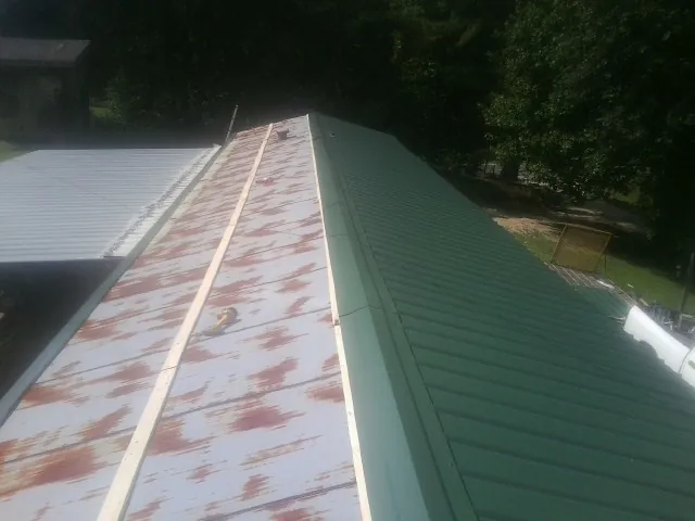 Old rusted panels beside newly installed green metal roofing — Wind Damage Roof Repair by Roofing Brothers in Delco