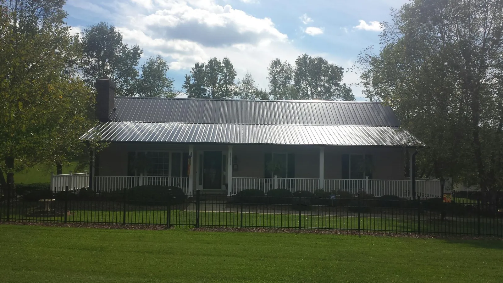 Gray metal roof on a brick ranch with a full width front porch — Gutter Guard Installation work by our crew in Delco