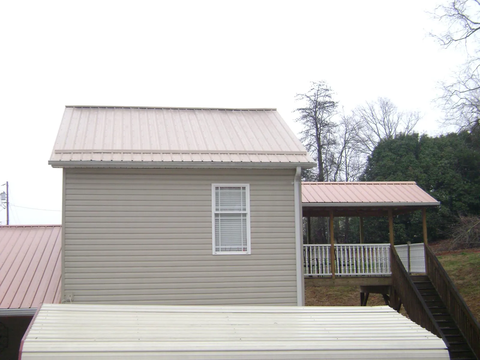 Tan metal roofs on a two story addition and attached porch, from a Roof Replacement job in Delco
